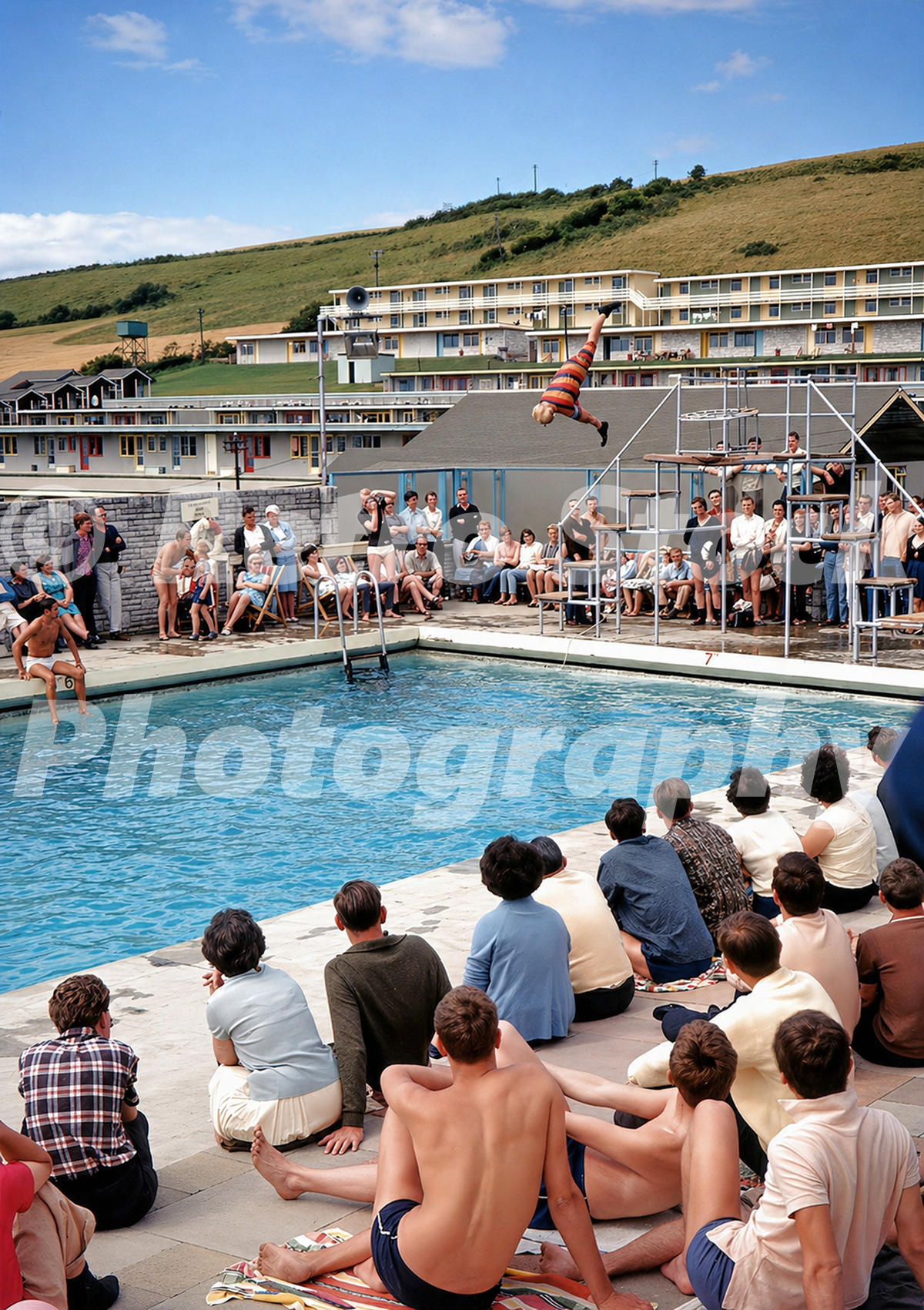Pontins Osmington Bay outdoor pool in the 1960s with a diving display, spectators, diving platform and hillside accommodation blocks