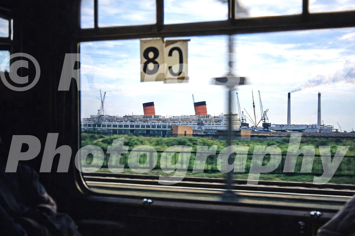 1950s view of RMS Queen Elizabeth at Southampton docks seen through the window of an approaching train.