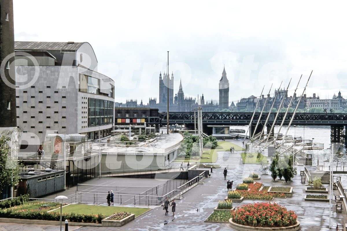 1950s view of Royal Festival Hall and the South Bank in London, with a tennis court, riverside gardens, Hungerford Bridge and the Houses of Parliament.