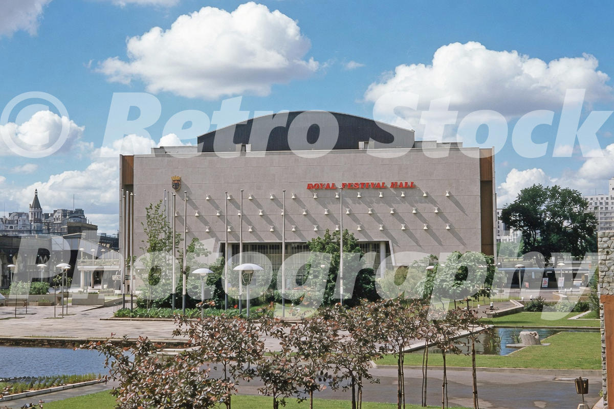 A 1950s colour photo of the rear exterior of the Royal Festival Hall on London's South Bank c1953, showing a cleared gravel landscape where the Festival of Britain structures once stood.