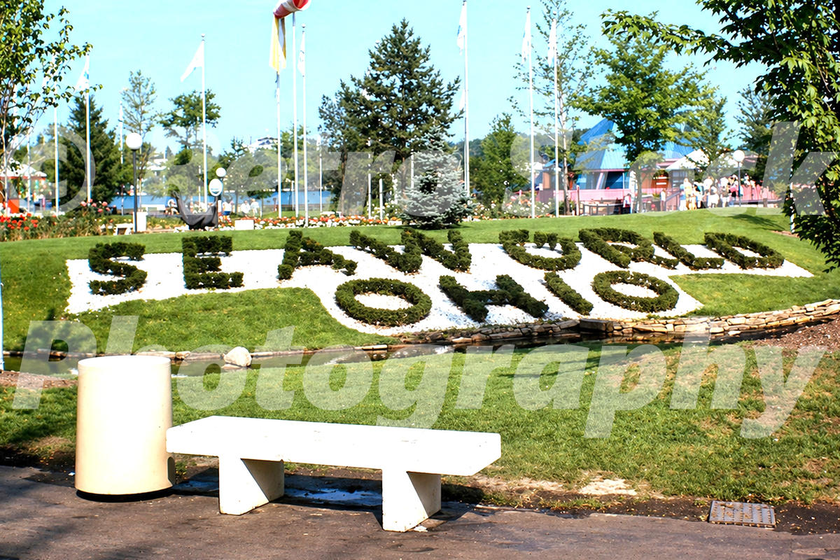 1970s view of the SeaWorld Ohio floral display in Aurora, with landscaped lettering, flags, lawns, flower beds and visitors.