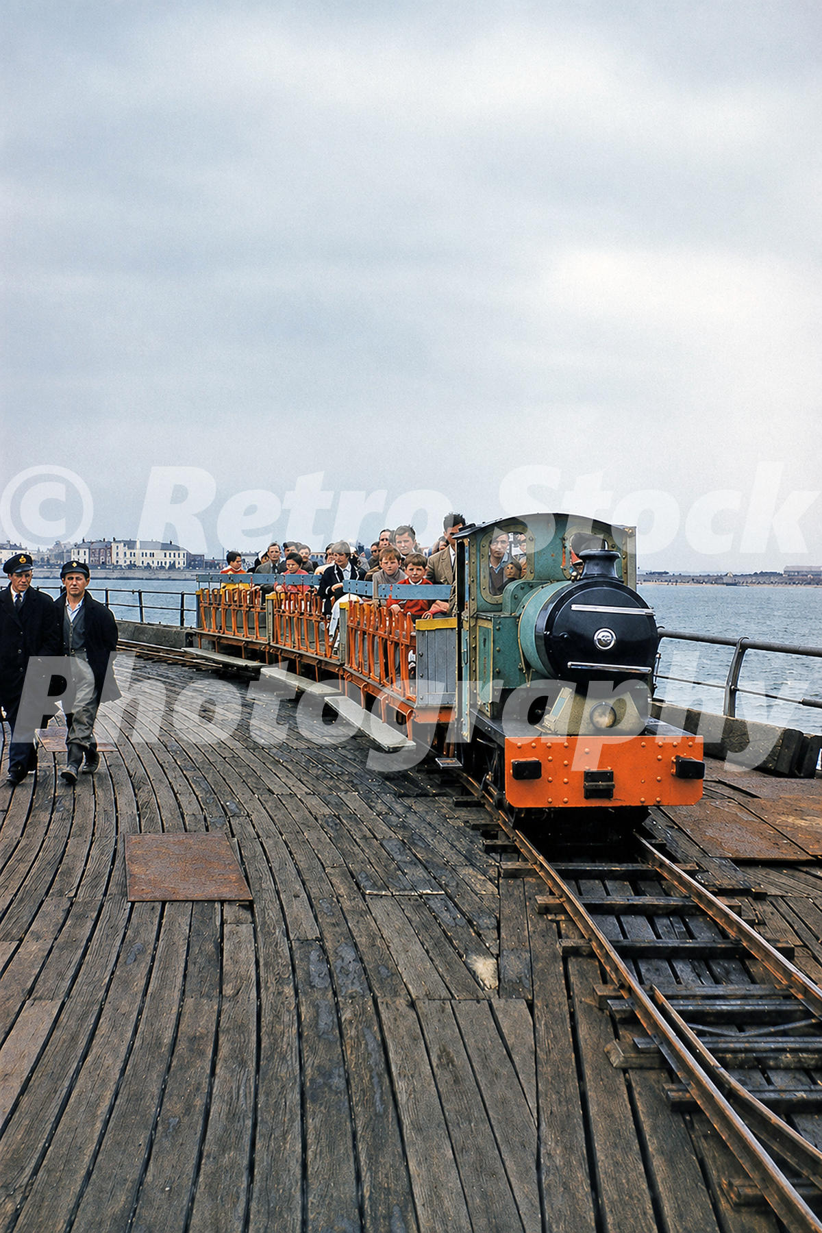 1950s view of Walton-on-the-Naze Pier Railway in Essex, with passengers riding behind Baguley diesel locomotive No. 3024 on the pier.