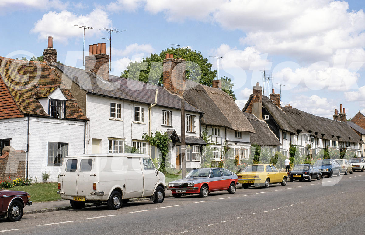 1980s colour photo of Wendover, Buckinghamshire, with thatched cottages, a Bedford CF van, an Alfasud Sprint and a yellow Vauxhall Chevette parked on the road.