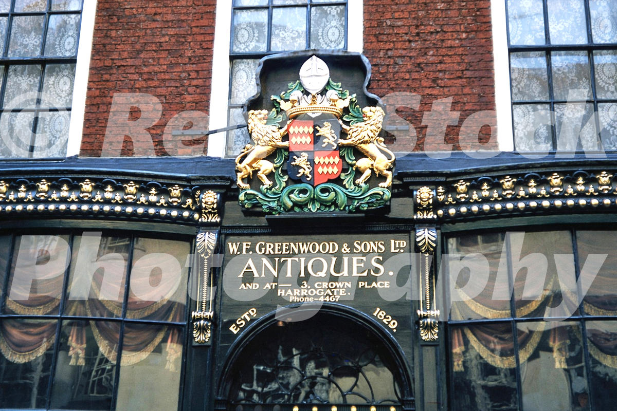 1950s colour photo of W. F. Greenwood & Sons antiques shopfront on Stonegate in York, with ornate signage and decorative windows.