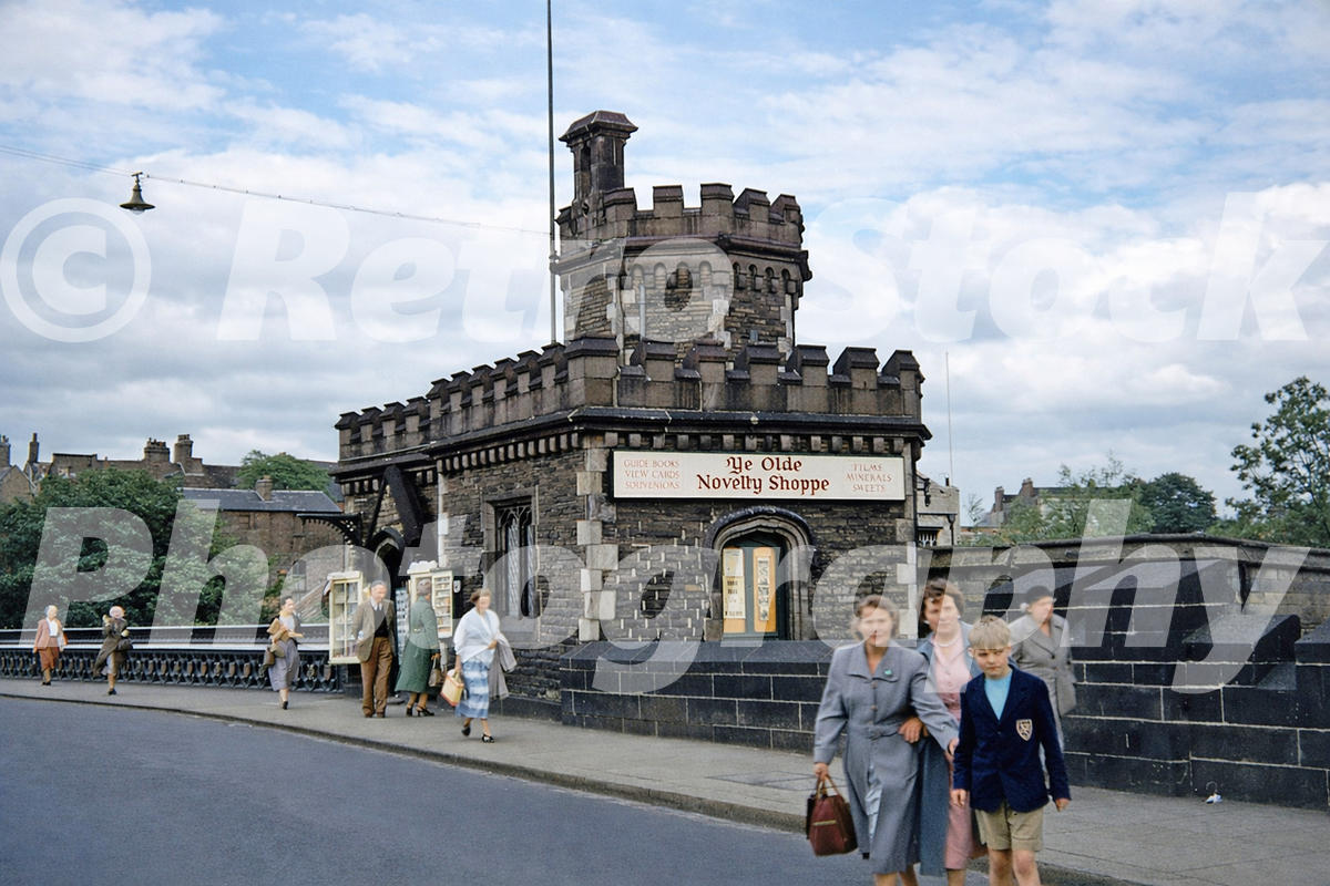 1950s colour photo of Ye Olde Novelty Shoppe in West Lodge on Lendal Bridge, York, with pedestrians passing outside.