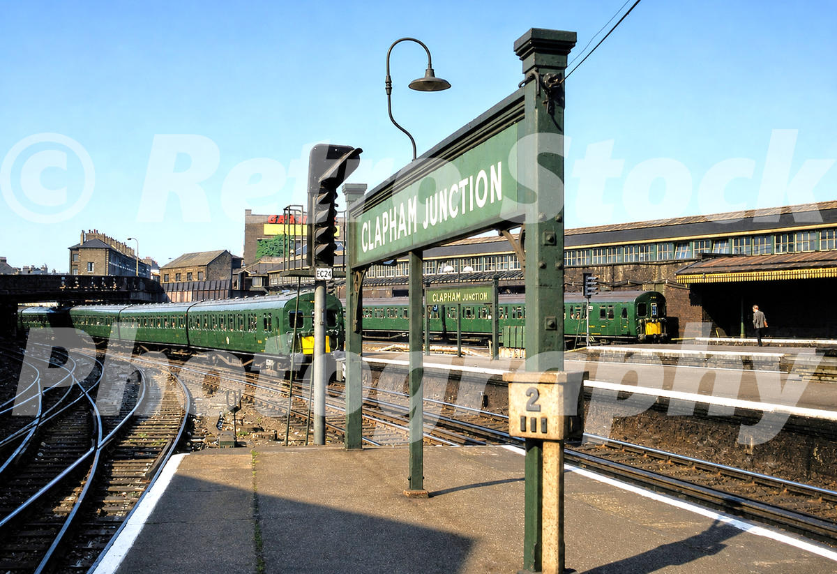 1960s view of Clapham Junction station in London, with green Southern Region electric trains, platform signs, tracks and the Odeon cinema sign in the background.