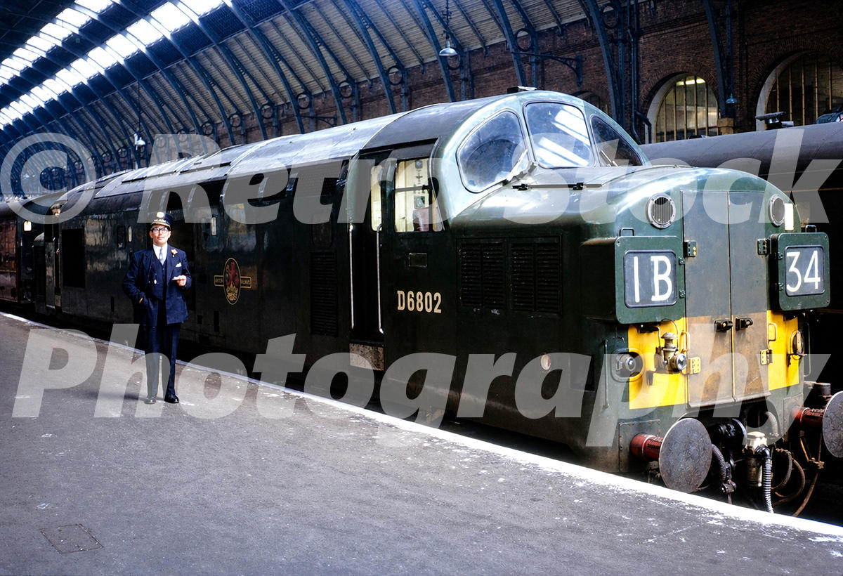 1960s view of Class 37 D6802 at King’s Cross station in London with headcode 1B34, a railwayman on the platform and the trainshed above