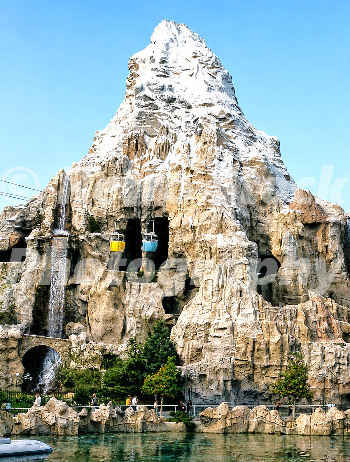 A 1960s color photo of the Matterhorn mountain at Disneyland in California, featuring Skyway buckets passing through the cavernous peak above a waterfall and the Submarine Voyage lagoon.