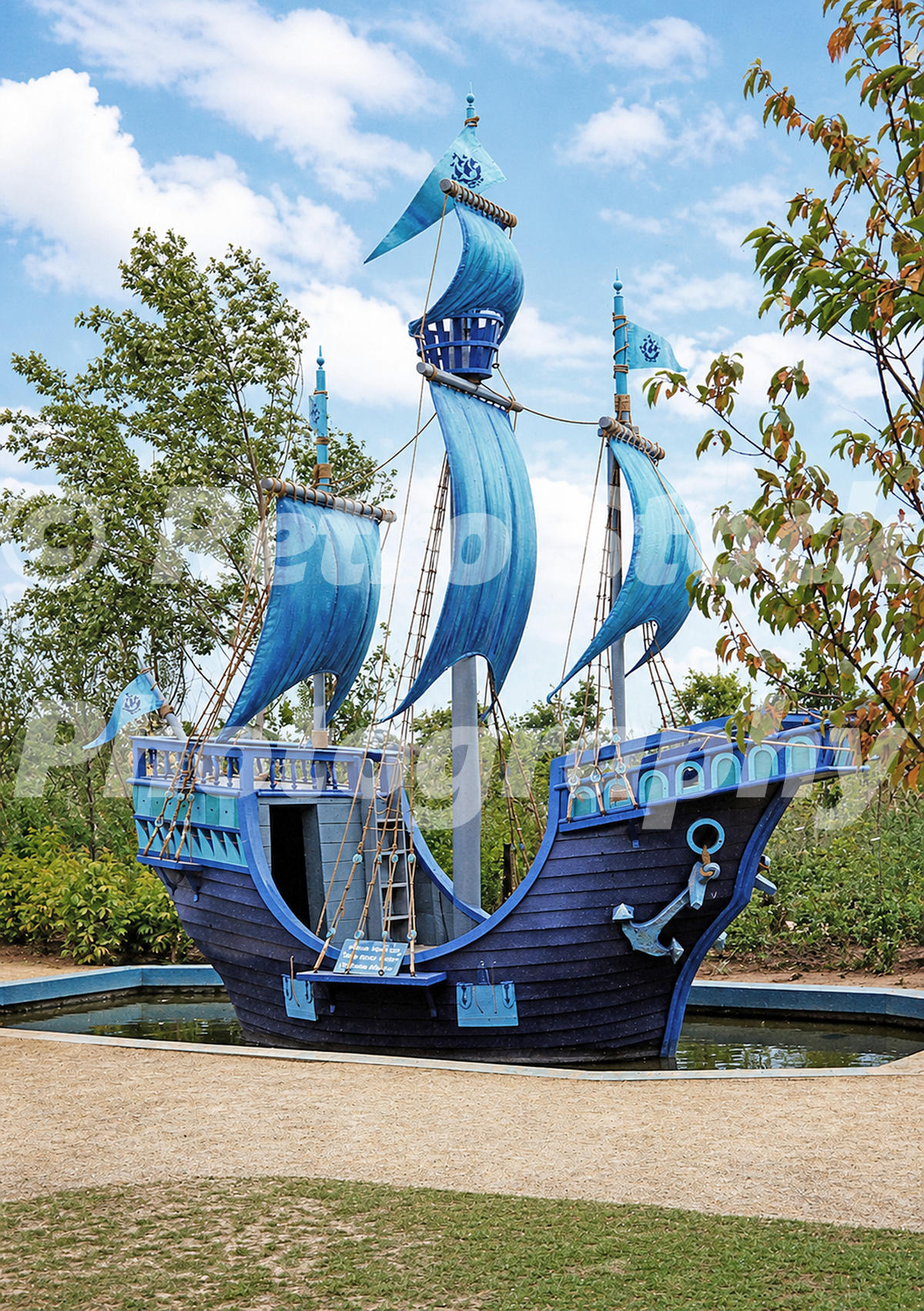 1980s view of the Blue Peter boat at the Liverpool Garden Festival, with blue sails, flags, rigging and a small surrounding pool.