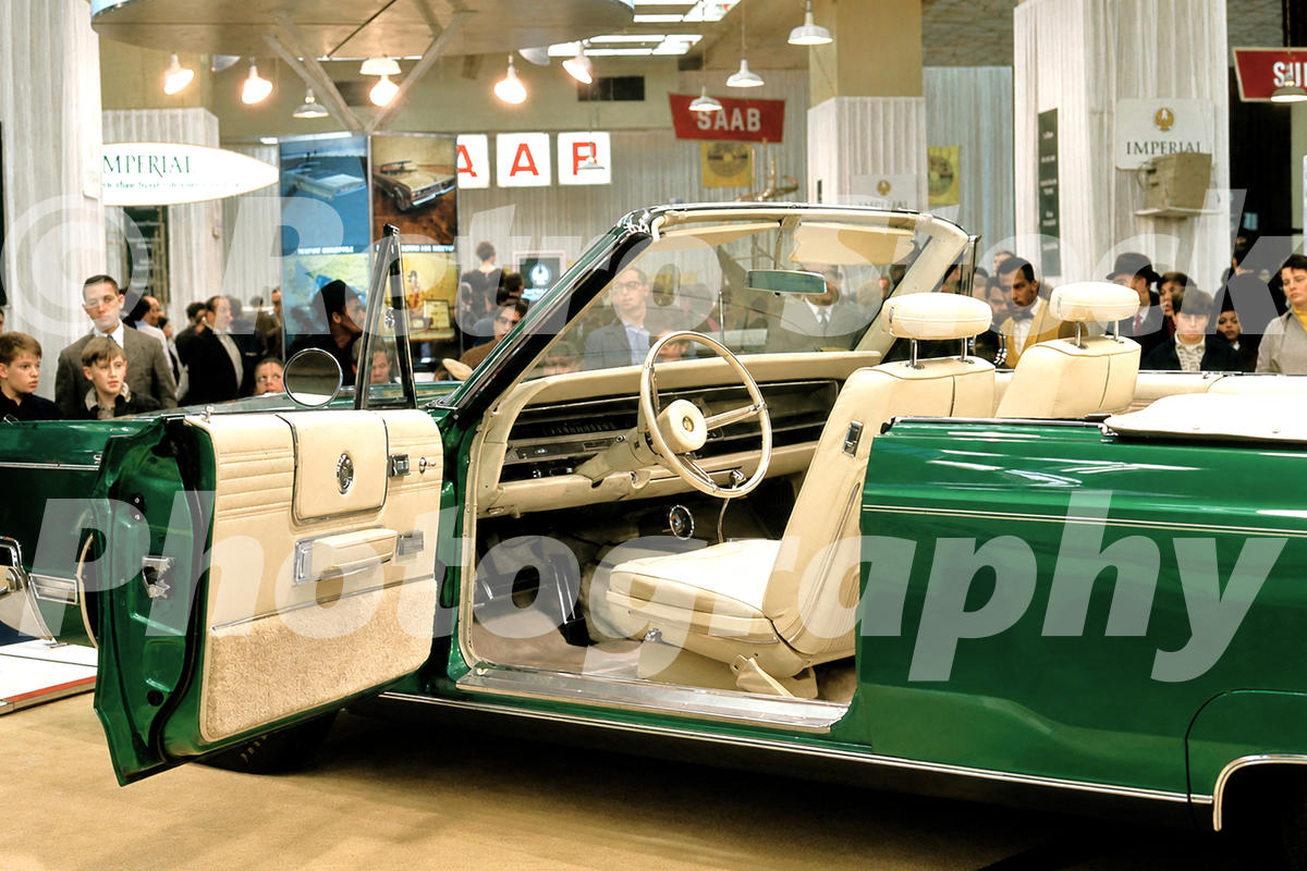 A 1960s color photo of a teal Chrysler 300 Convertible with its door open at the 1968 New York Auto Show, showing the cream leather interior and Imperial signage in the background.