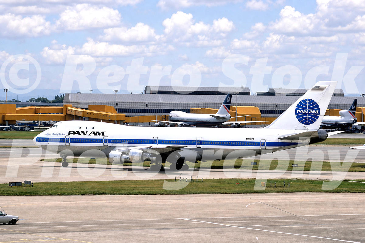 1980s color view of Pan Am Boeing 747 Clipper Maid of the Seas at Heathrow Airport, with terminal buildings and other aircraft behind.