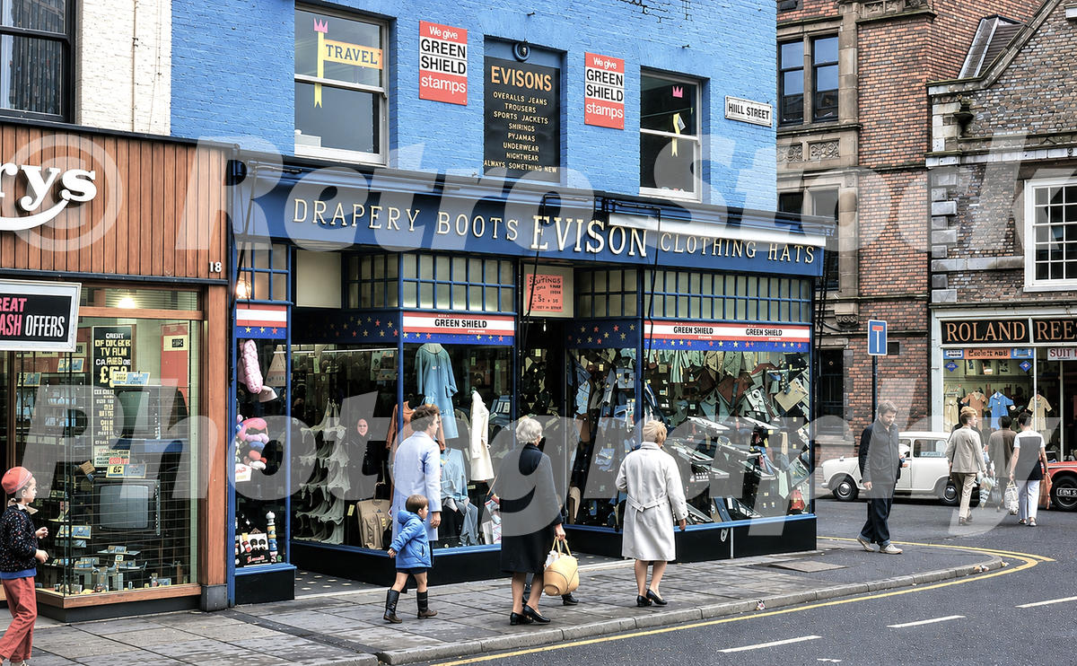 1970s view of Evison clothing and drapery shop on High Street in Wisbech, with Green Shield stamp signs, pedestrians, Hill Street and nearby shopfronts.