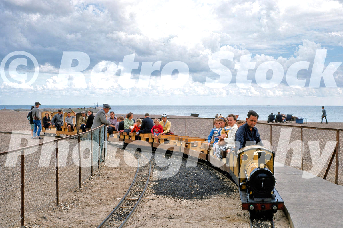 1950s view of Hastings Miniature Railway at Marine Parade station, with Firefly locomotive arriving beside the beach and sea.