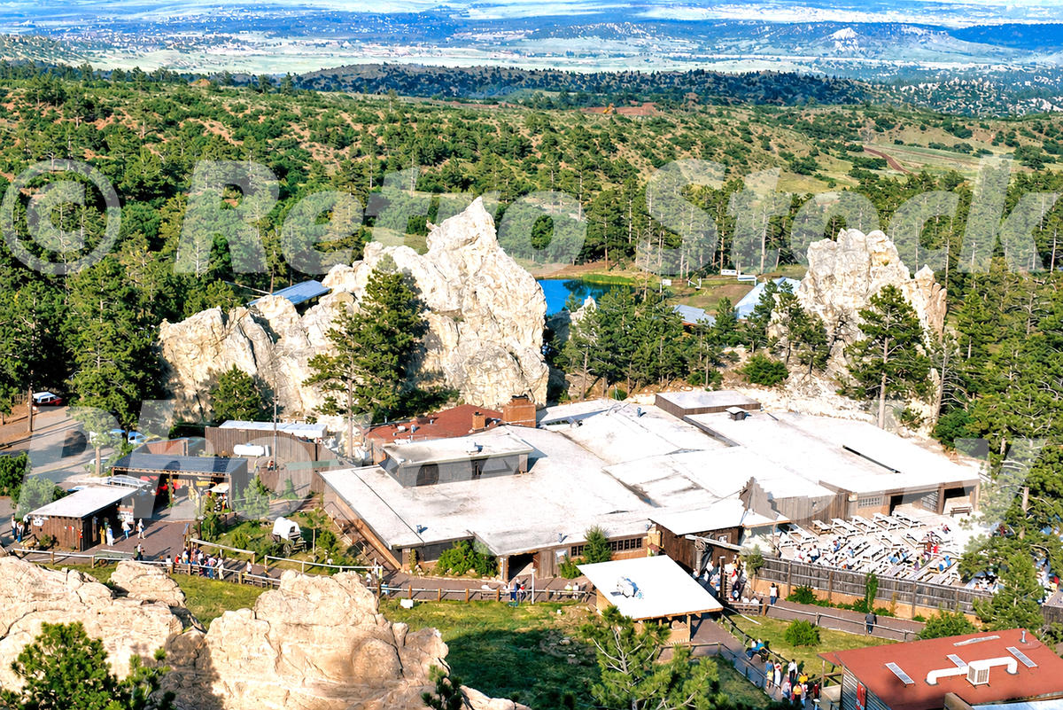 1970s color view of the Flying W Ranch near Colorado Springs, Colorado, with Western-style buildings, white rock formations, pine trees and mountain scenery.