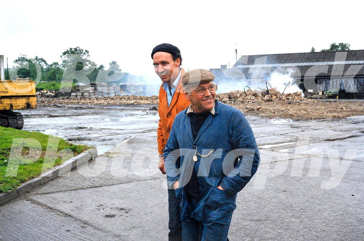 1980s view of Fred Dibnah at the Redland Roof Tile factory in Leighton Buzzard, with smoking chimney rubble and industrial buildings in the background.