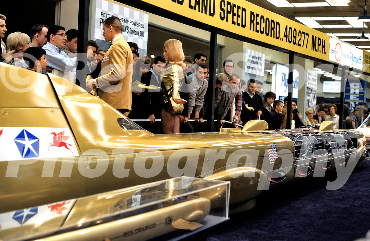 A 1960s color photo of the Goldenrod land speed record car on display at the 1966 New York Auto Show, featuring its streamlined gold body and four Chrysler Hemi engines.