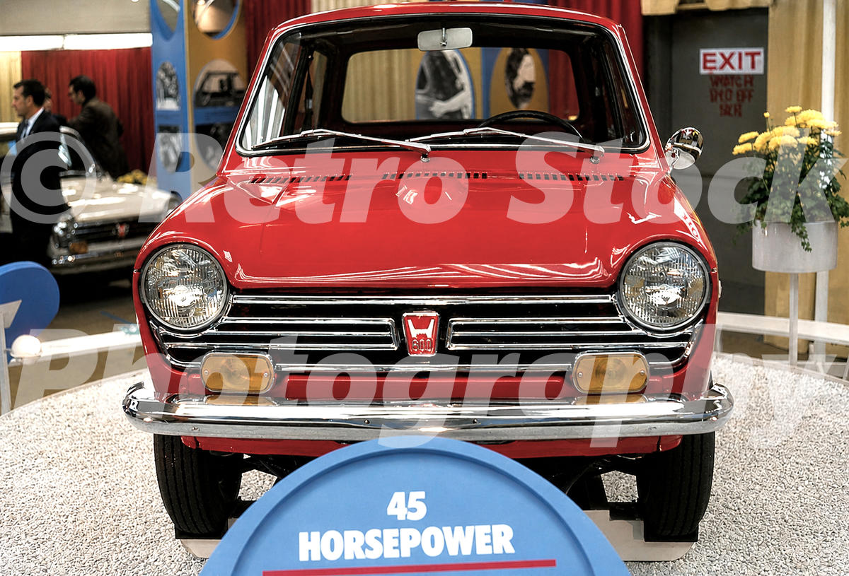 A 1960s color photo of a bright red Honda N600 on display at the 1968 New York Auto Show, with a blue sign in the foreground reading 45 HORSEPOWER.
