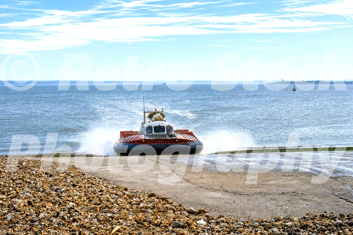 1960s view of a Hoverwork SR.N6 hovercraft landing at Southsea, with spray, pebble beach and the Solent beyond.