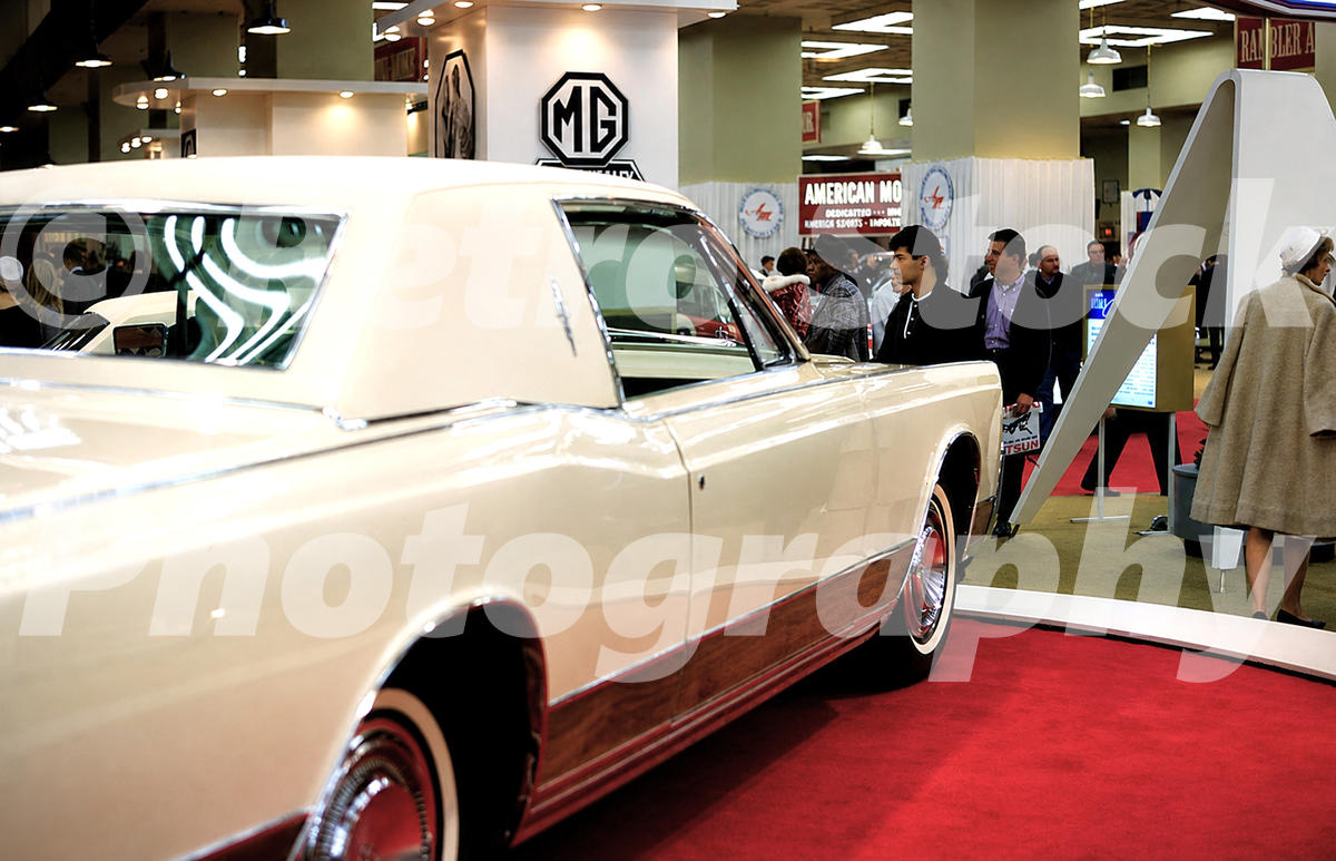 A 1960s color photo of the Lincoln Continental Coronation Coupe show car on a red carpet at the 1966 New York Auto Show, with MG and American Motors signage in the background.