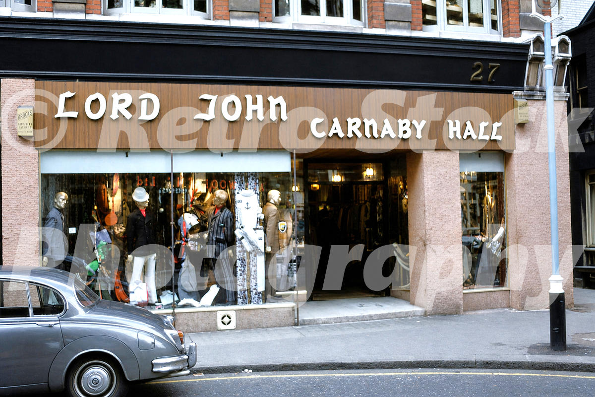 1960s view of Lord John menswear shop on Carnaby Street in London, with mannequins, fashion displays and a Jaguar parked outside.