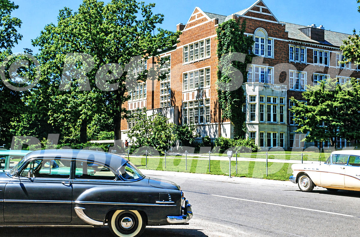 A 1950s color photo of Landon Hall at Michigan State University in East Lansing, featuring its red brick Collegiate Gothic architecture and vintage cars parked in the foreground.