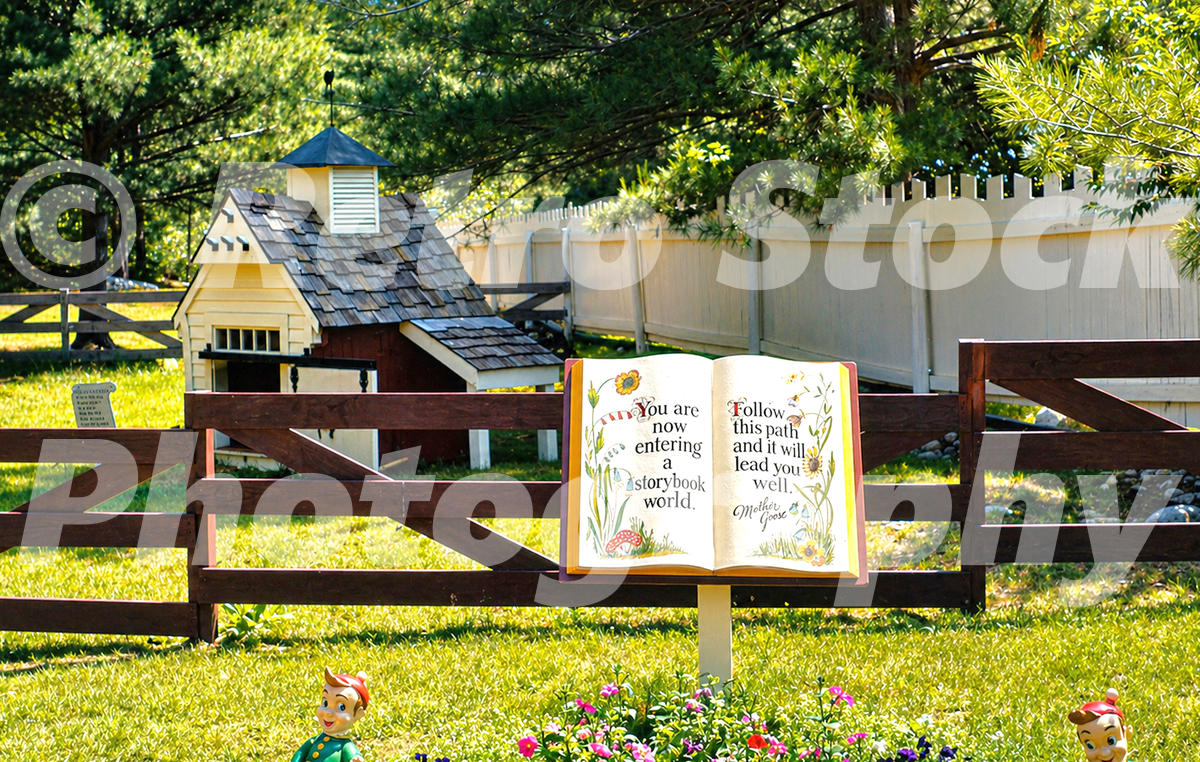 1950s color view of a Mother Goose storybook sign at Story Land in Glen, New Hampshire, with a miniature farm building, fence and nursery-rhyme figures.