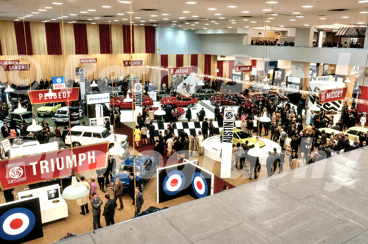 A 1970s colour photo taken from a high-angle balcony looking down at the British Leyland, BMW, and Peugeot stands at the 1970 New York Auto Show.