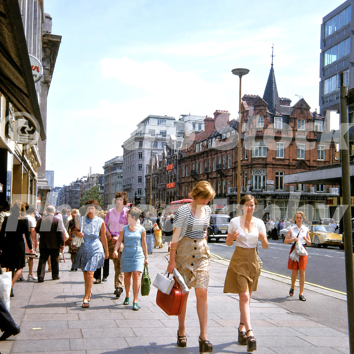 1970s view of Oxford Street in London near Selfridges, with shoppers, buses, cars, banks and commercial buildings.
