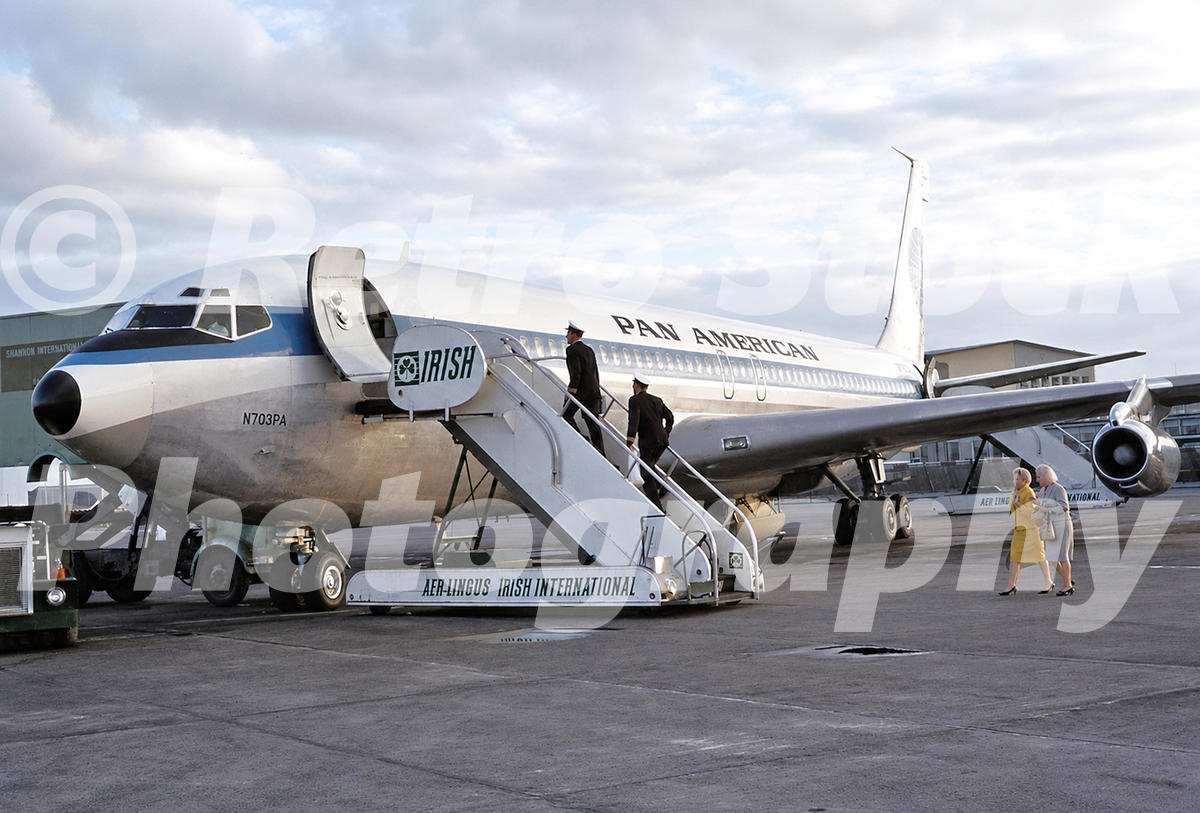 1960s view of Pan Am Boeing 707 N703PA at Shannon Airport, with Aer Lingus mobile stairs, boarding passengers and apron buildings.