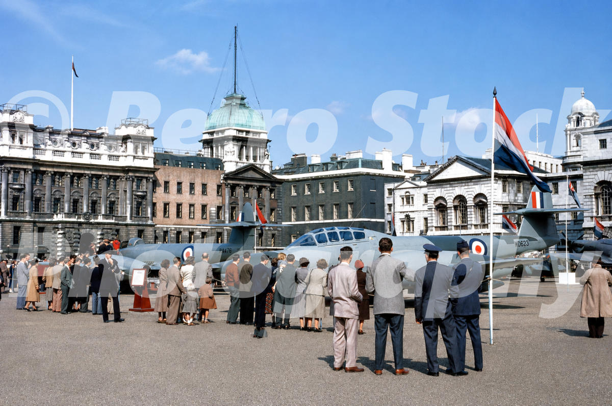 A 1950s colour photo of two Gloster Meteor jet aircraft on public display at Horse Guards Parade in London, with the Admiralty Extension in the background.