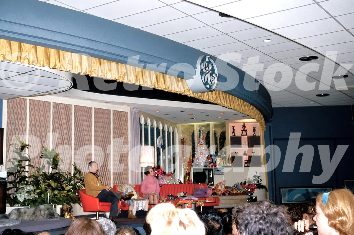 1960s color view inside the Progressland Theatre at the GE Pavilion, New York World’s Fair, showing a Carousel of Progress living-room scene, GE logo and seated audience.