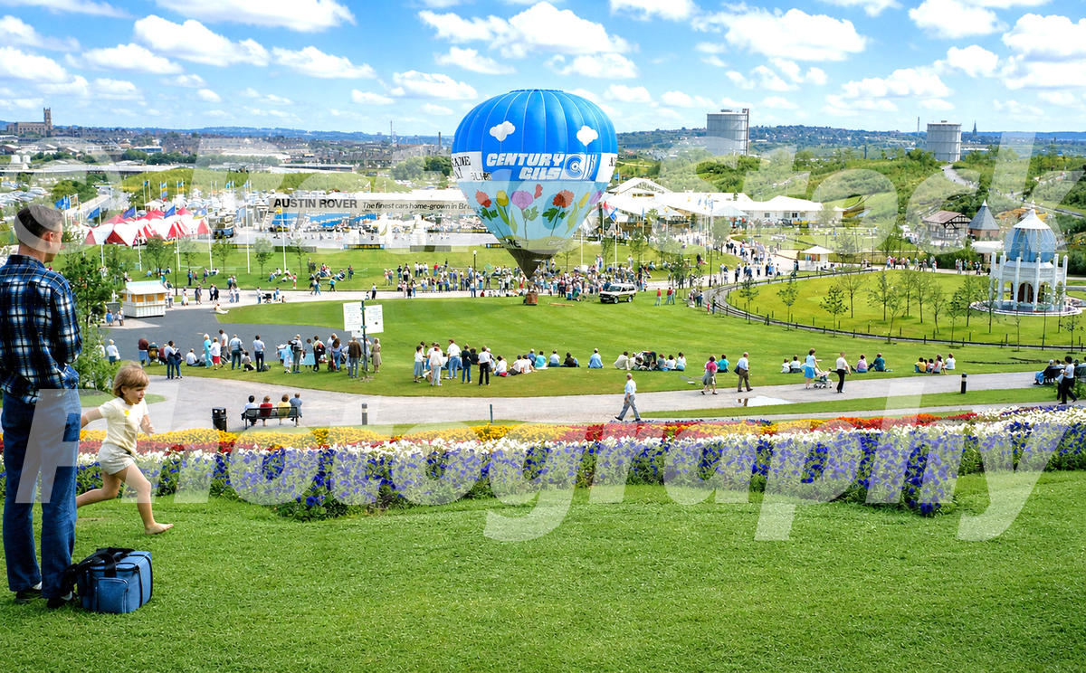 1980s view of the Stoke-on-Trent Garden Festival, with visitors, flower beds, exhibition buildings, Austin Rover signage and a Century Oils hot-air balloon.