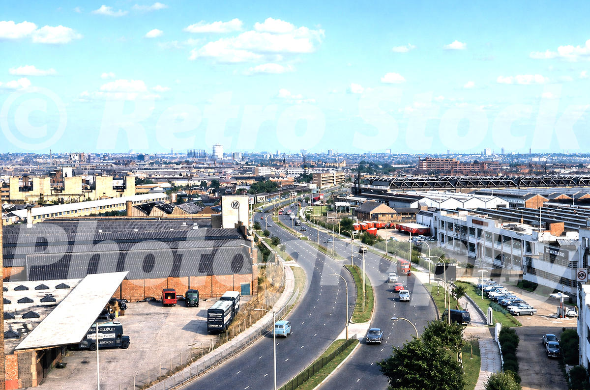 1960s view of Western Avenue at Park Royal in London, looking east from Park Royal Underground station over factories, warehouses, traffic and industrial buildings.